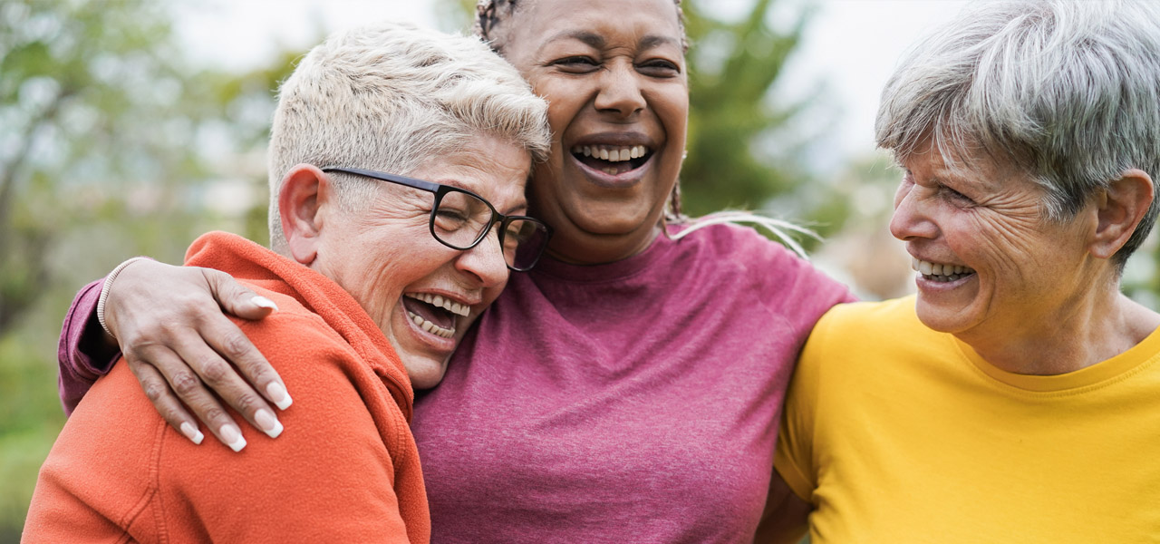 image of three mature woman hugging and laughing