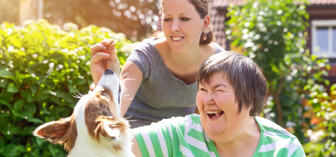 image of an additional needs a dult with her dog and a carer